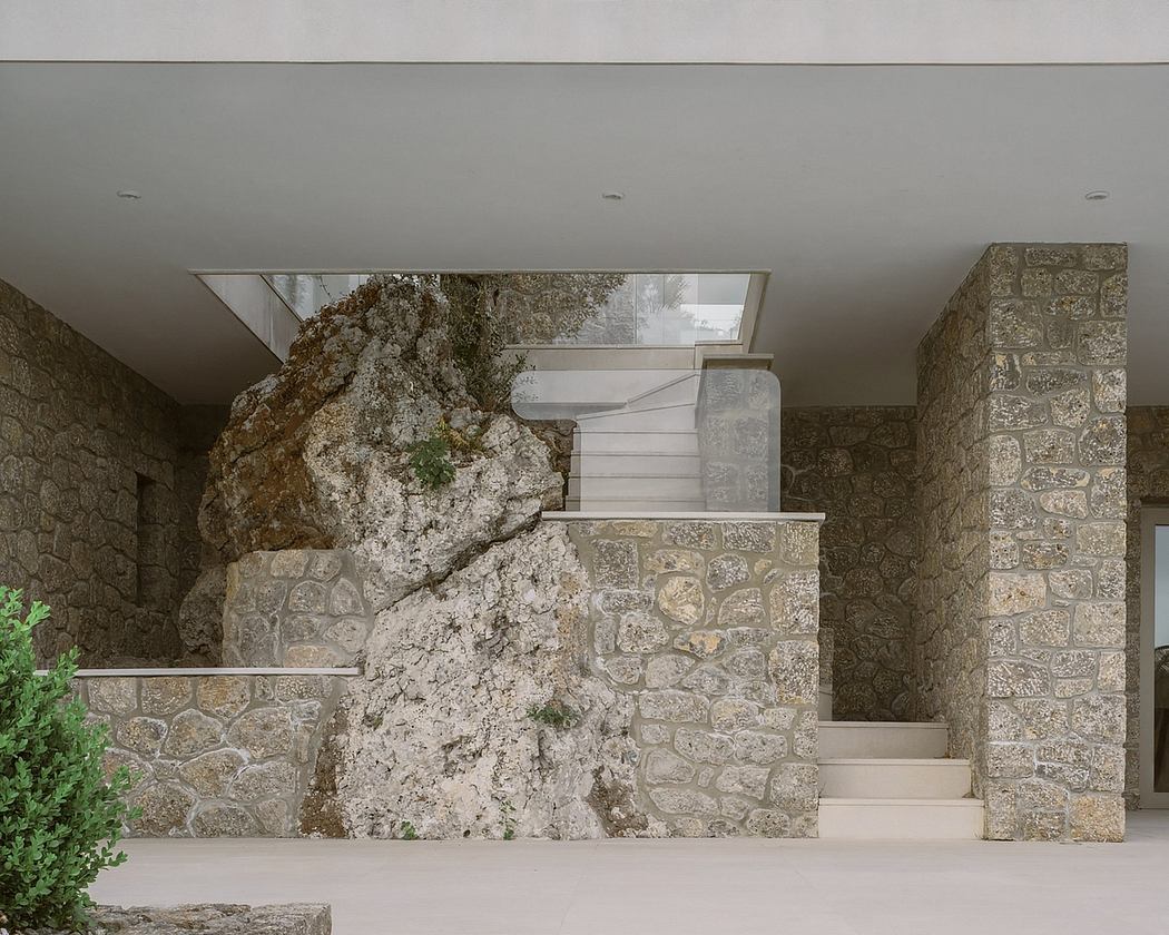 An indoor staircase with a large, natural stone feature wall and modern glass architecture.