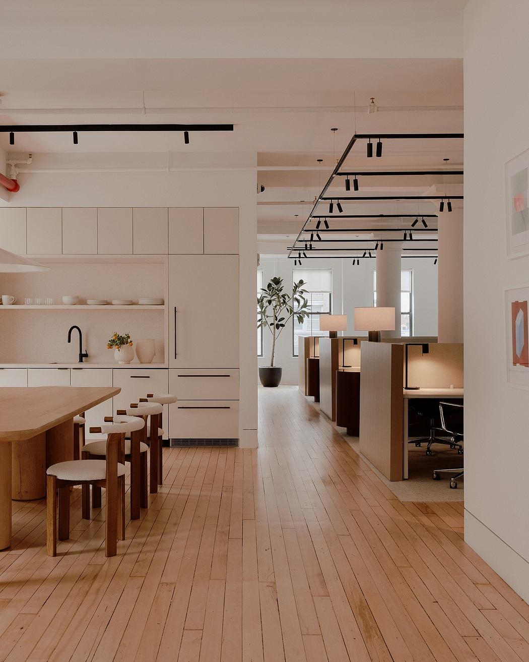 Minimalist open-concept kitchen and office space with sleek white cabinetry and pendant lighting.