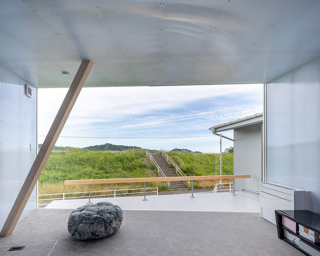 Modern, minimalist interior with expansive views of a grassy landscape and stairs leading to the outdoors.