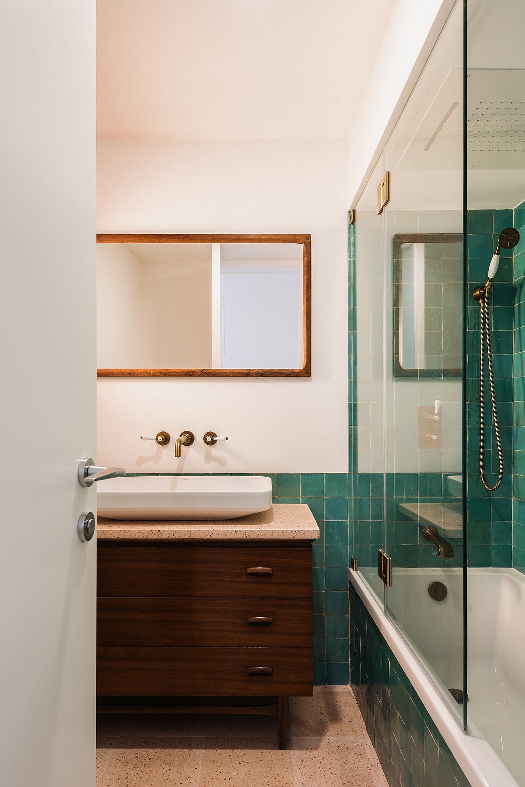 Modern bathroom with wooden vanity, green tiled walls, and recessed mirror.