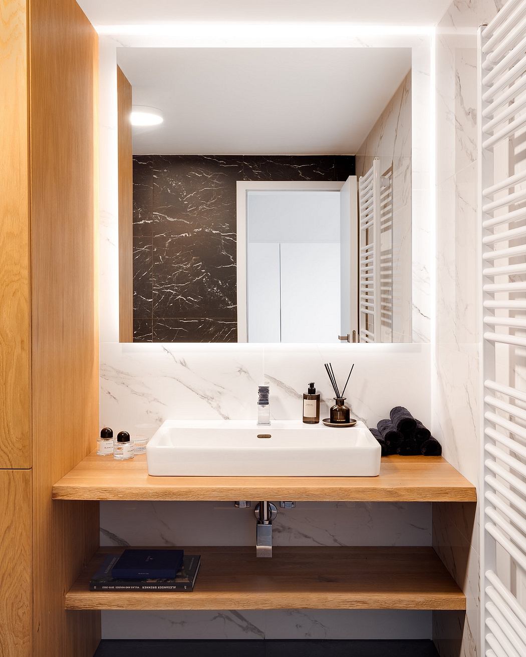 Minimalist bathroom design with wooden vanity, marble accents, and recessed lighting.