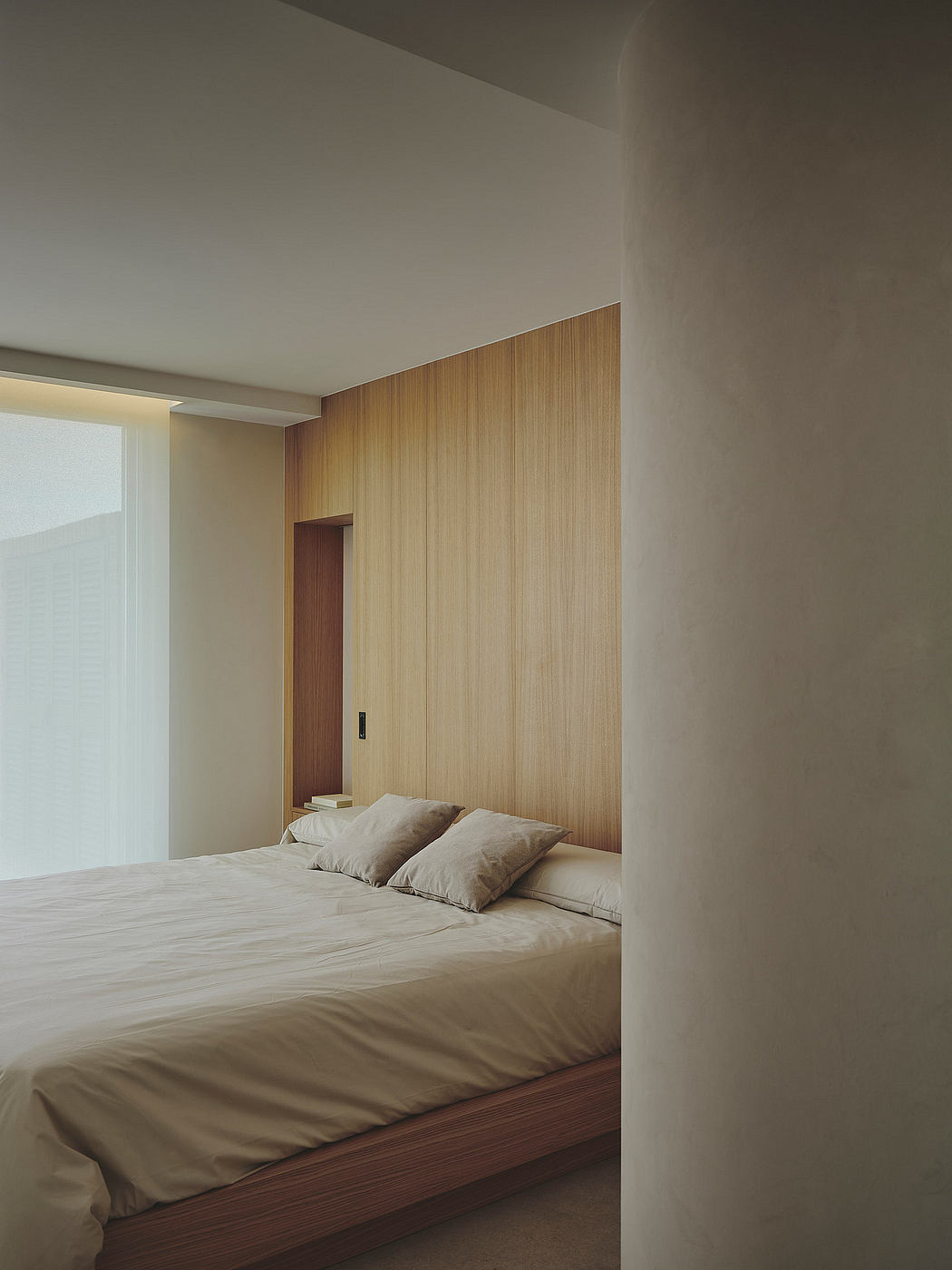 Minimalist bedroom with wooden accent wall, neutral bedding, and clean lines.