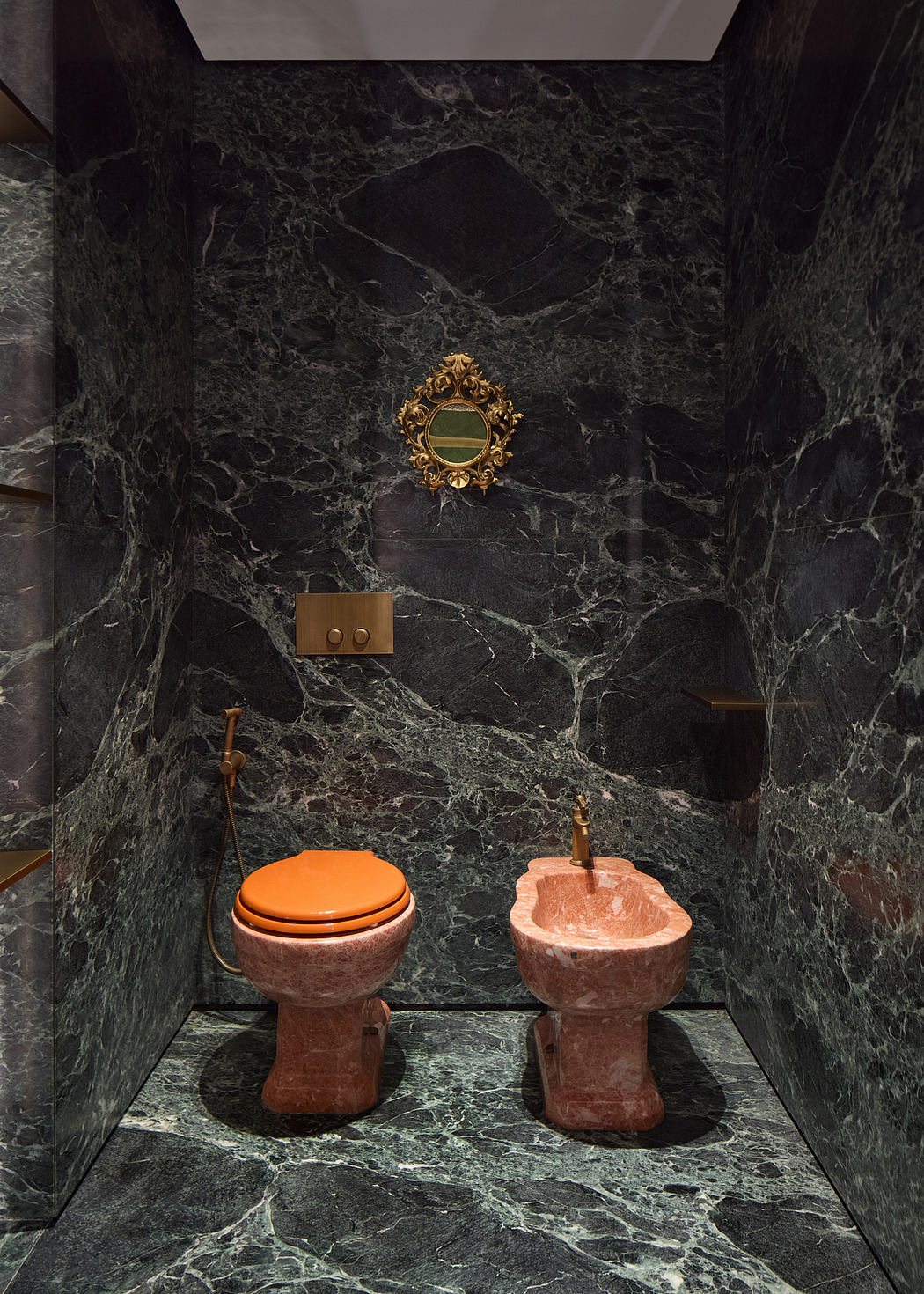 A luxurious bathroom with black marble walls, ornate gold mirror, and modern fixtures.
