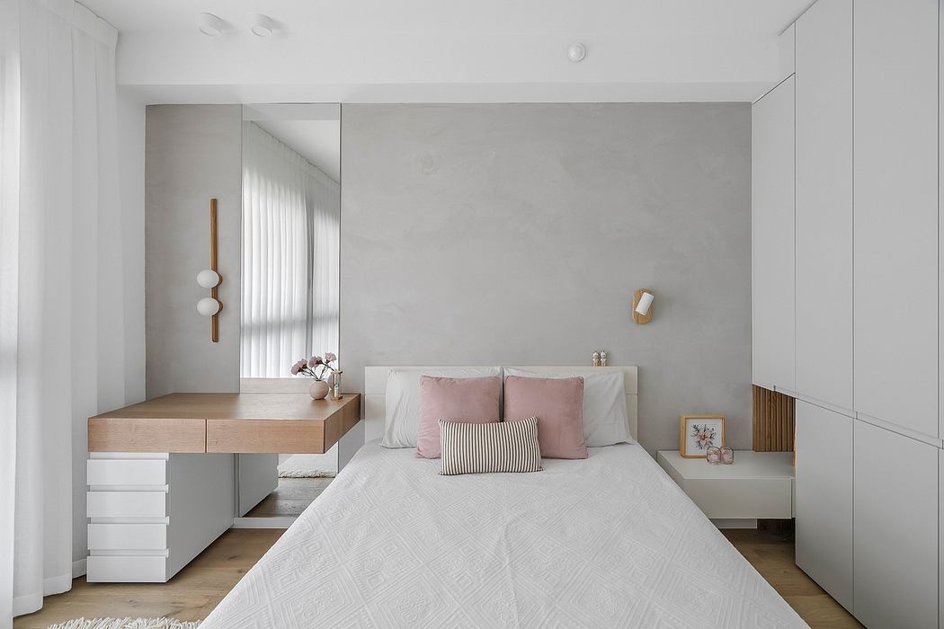 Minimalist bedroom with gray walls, wood accents, and pink textiles. Sleek built-in furniture.