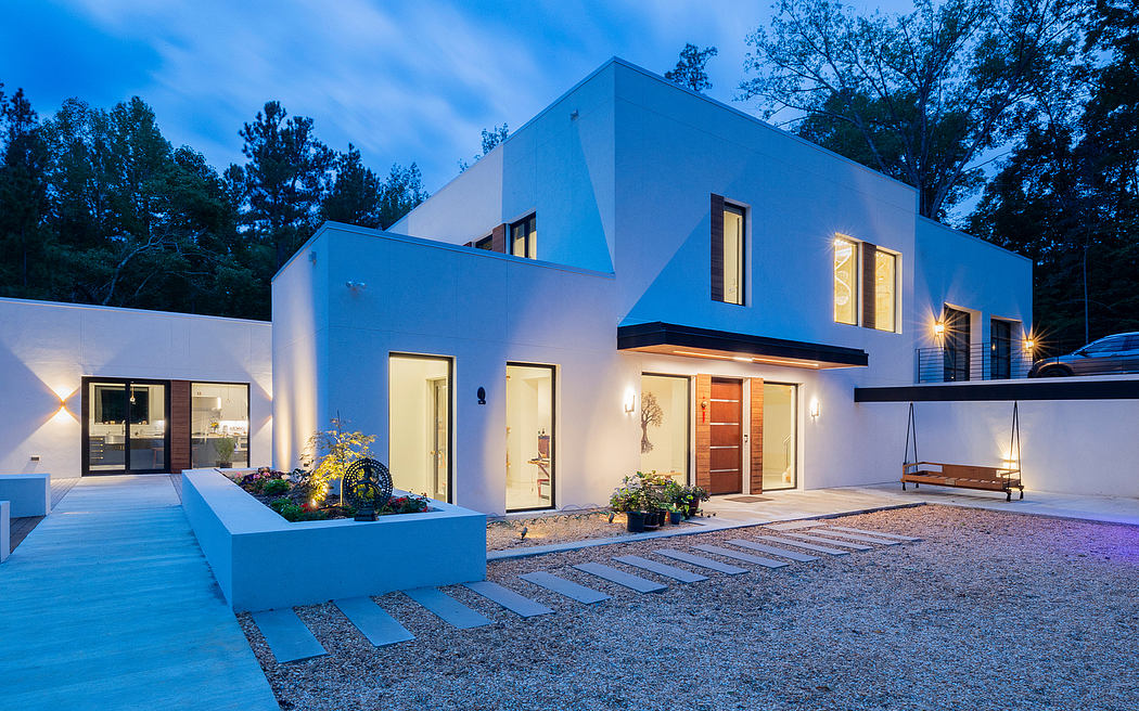 Modern two-story house with sleek white exterior, patio, and exterior lighting.