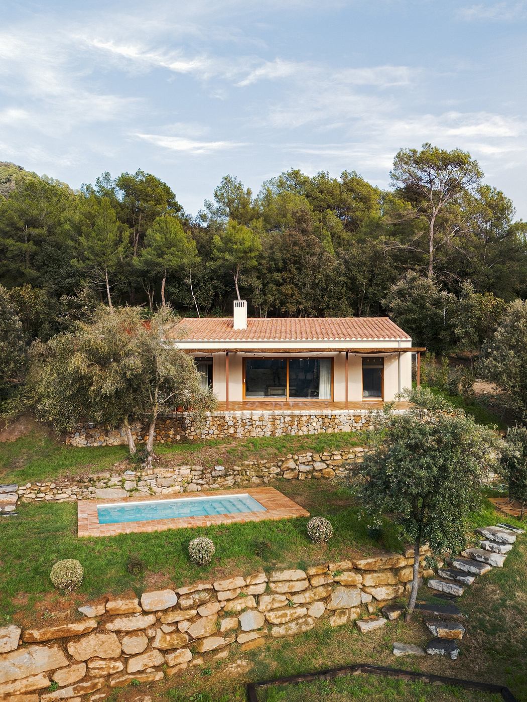 A charming stone house nestled in lush greenery, featuring a pool and terrace with scenic views.