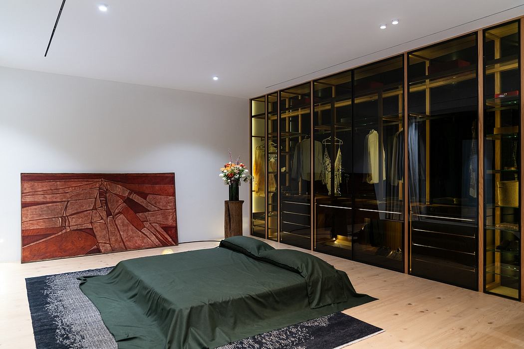 Sleek, contemporary bedroom with a glass-enclosed wardrobe, wooden artwork, and hardwood flooring.