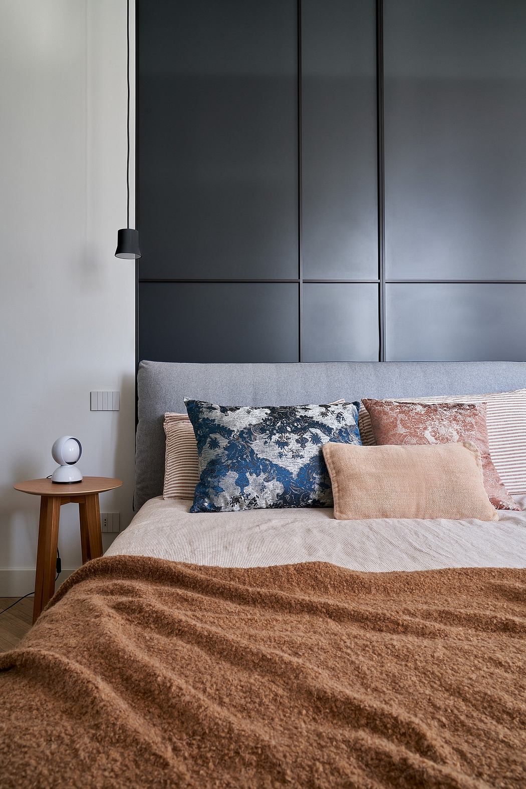 Modern bedroom with sleek black cabinetry, layered neutral bedding, and plush throw.
