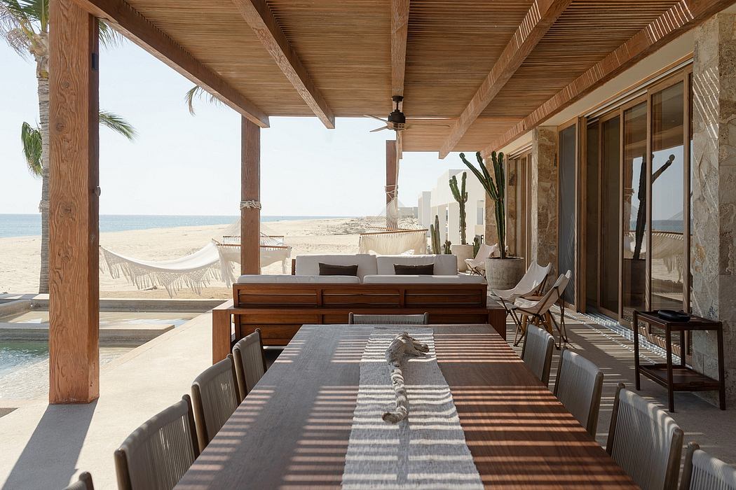 A rustic, beachfront patio with a wooden ceiling, hammock, and minimalist furniture.