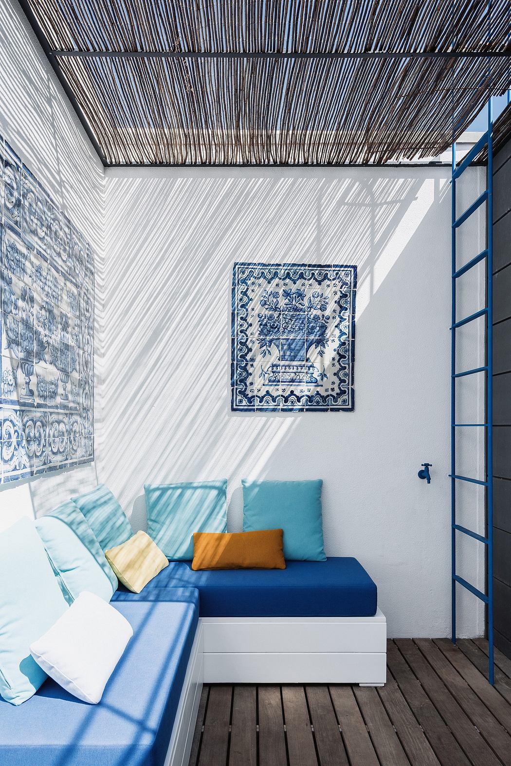 A cozy outdoor seating area with a thatched roof, patterned tiles, and plush cushions.