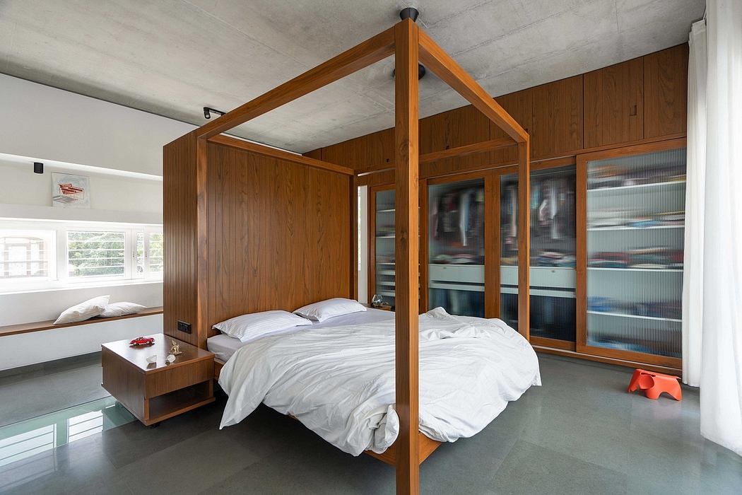 Spacious modern bedroom with wooden canopy bed, glass cabinets, and concrete floor.