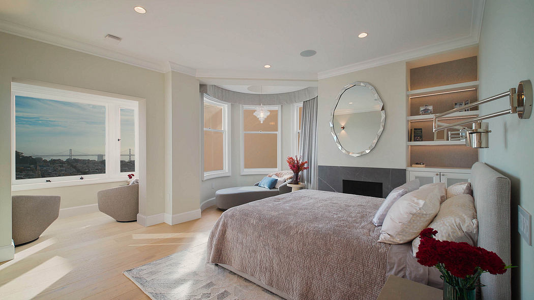 Spacious, modern bedroom with bay window, fireplace, and circular mirror. Elegant decor.