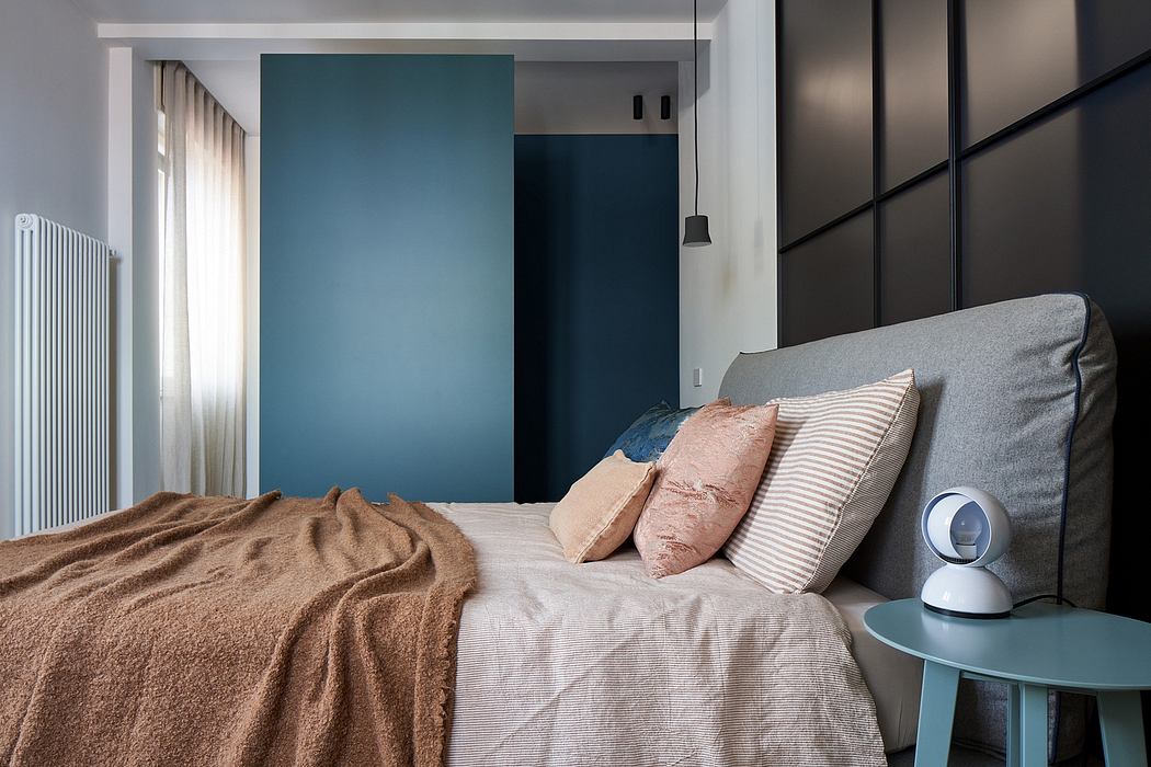 Modern bedroom with gray upholstered headboard, striped bedding, and minimalist decor.