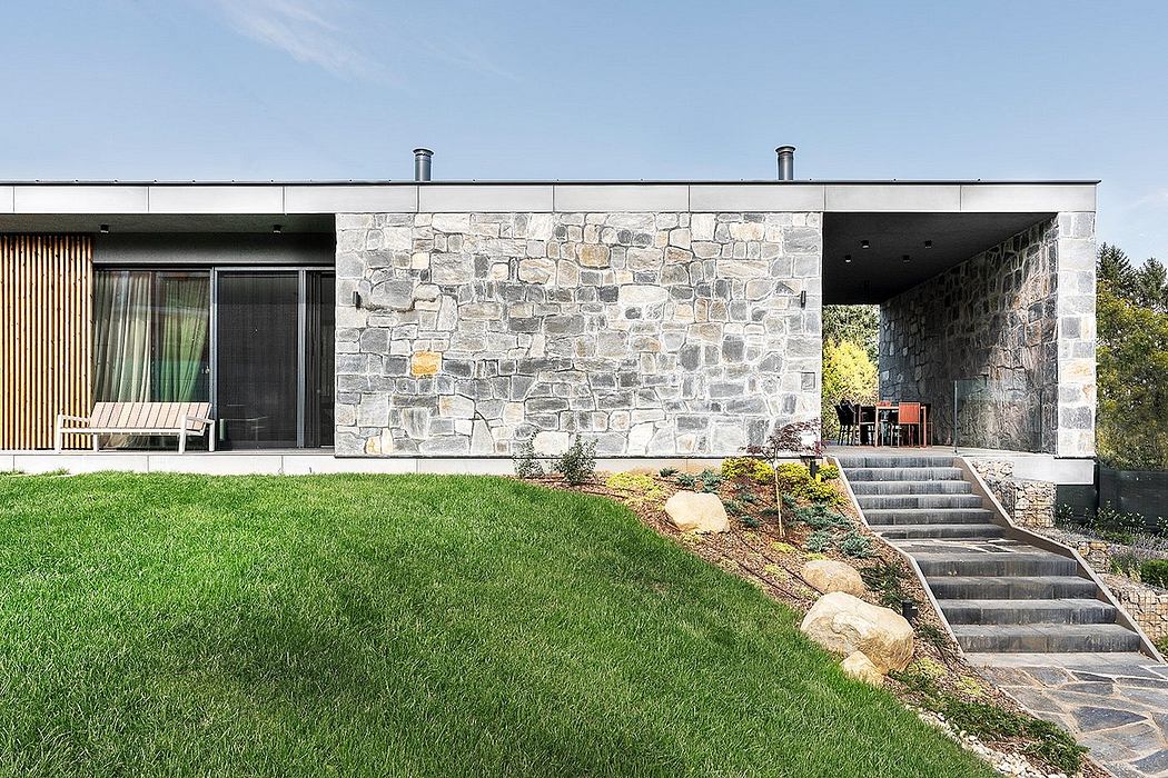 Single-story modern home with stone exterior, pitched roof, and extensive outdoor spaces.