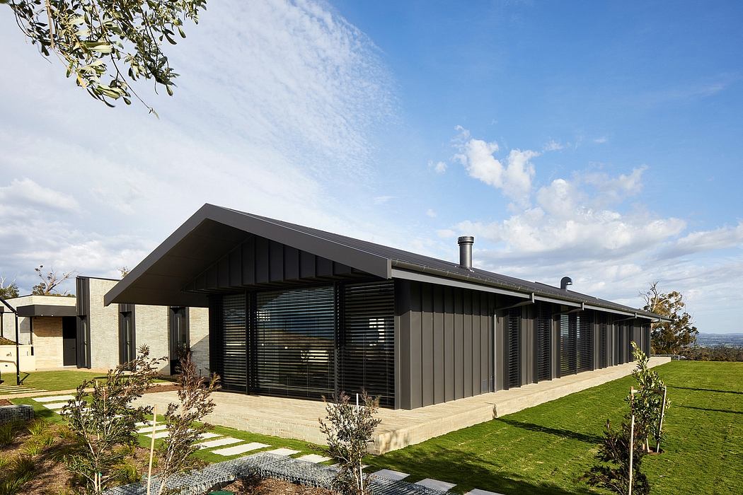 A modern cabin-style building with sleek black siding, large windows, and a sloped roof.