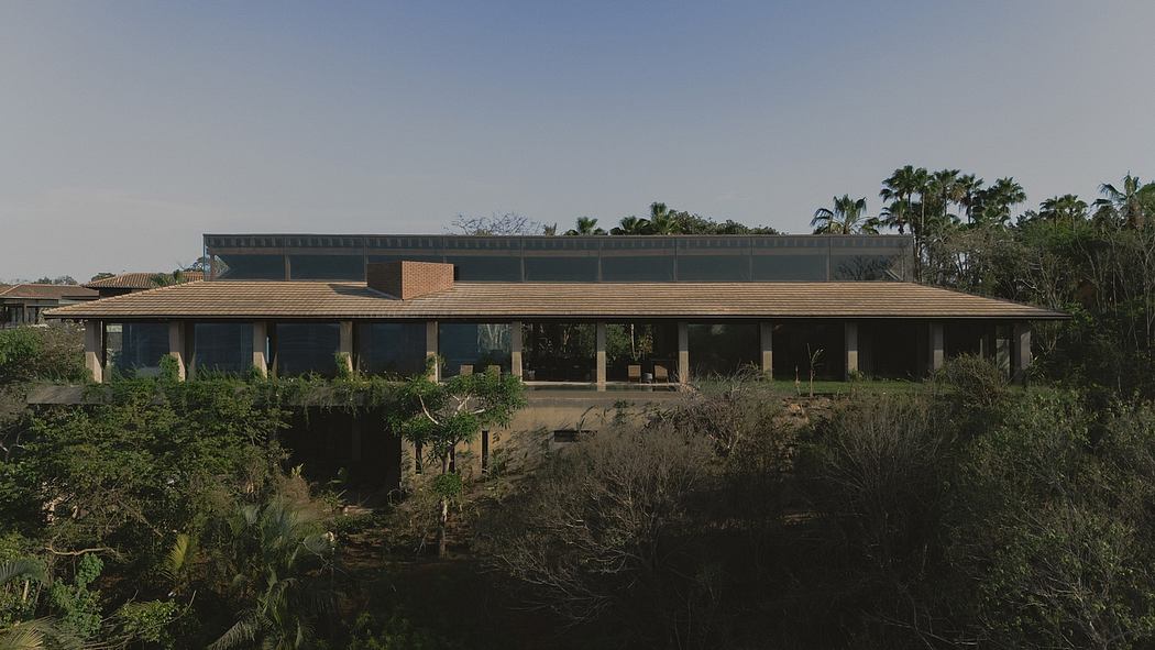 A modern, single-story building with a wide overhanging roof, surrounded by lush vegetation.
