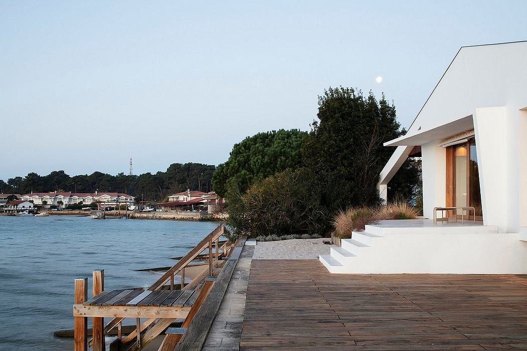 Modern waterfront architecture with wooden dock, steps, and minimalist exterior.