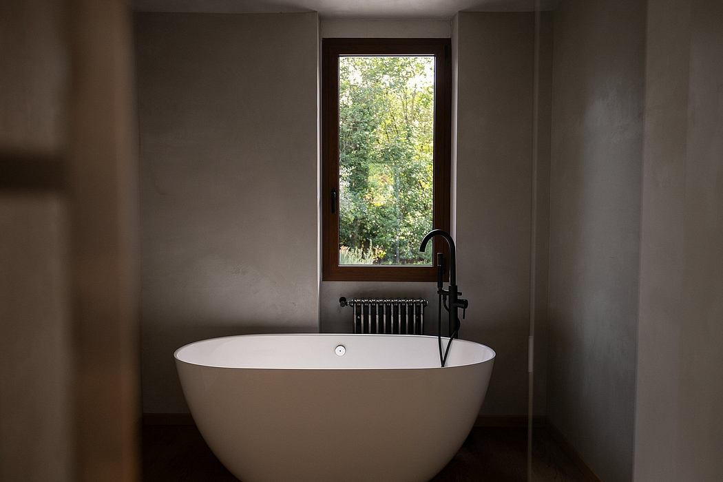 A modern bathroom with a free-standing bathtub and a large window overlooking greenery.