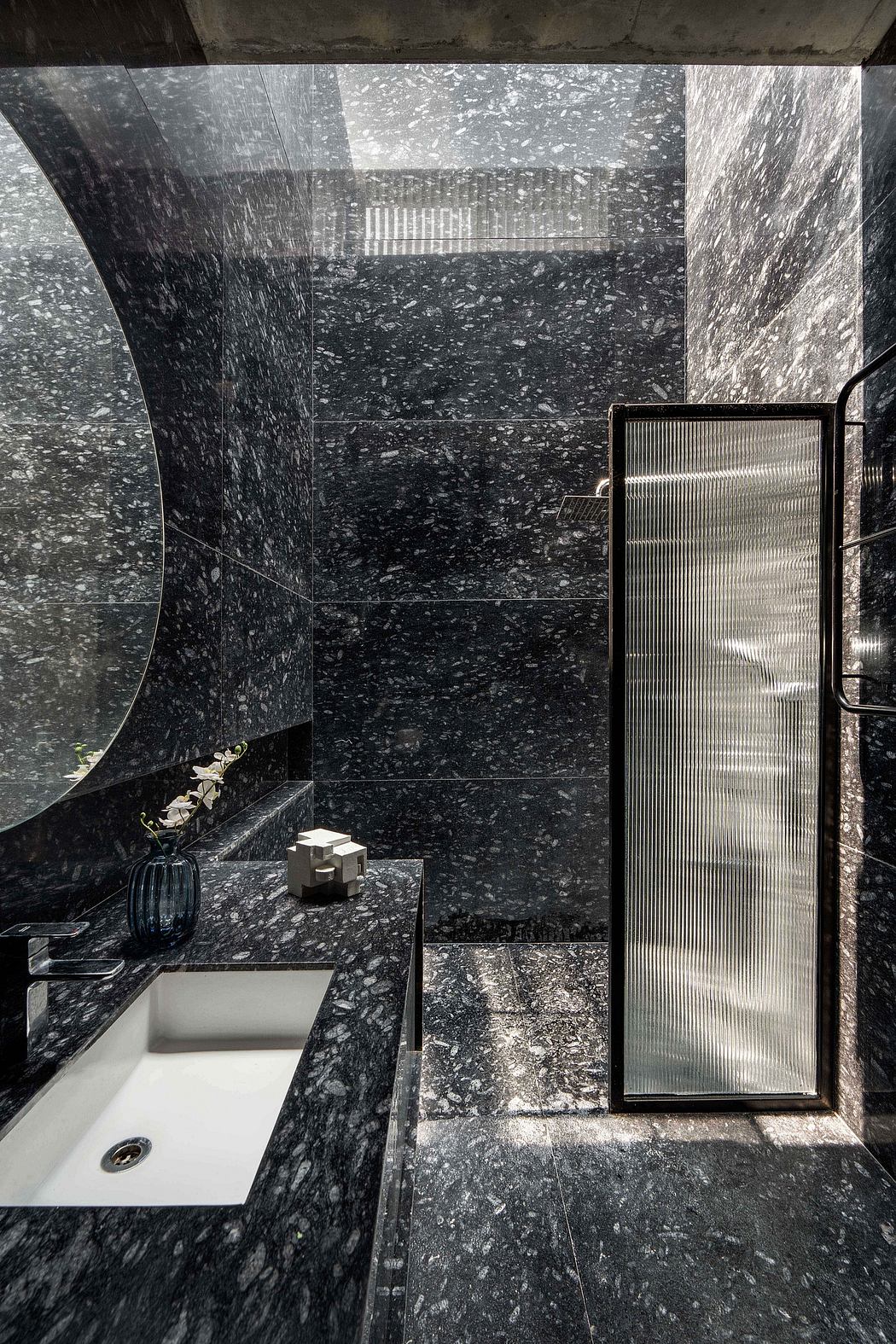 A sleek, modern bathroom with dark marble walls, a minimalist sink, and frosted glass details.