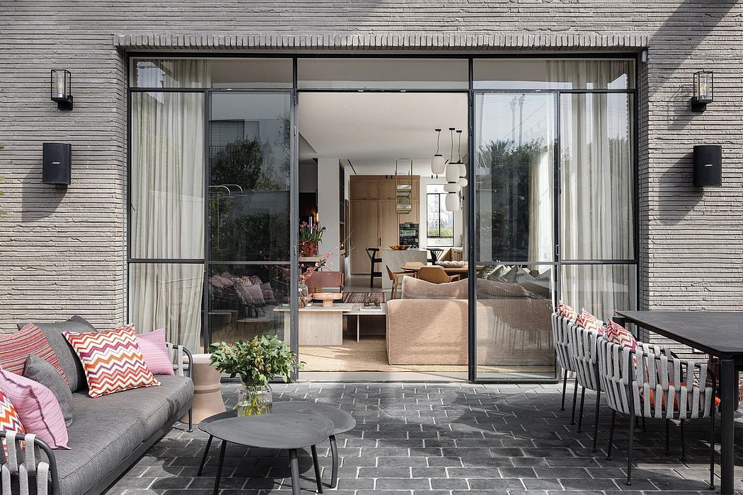 Glass wall framed home with sleek metal furniture and textured brick exterior.