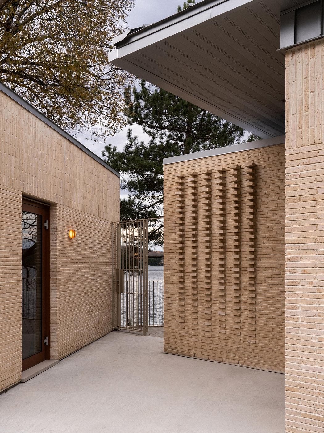 A modern brick building with a slanted roof, decorative exterior, and an ornamental gate.