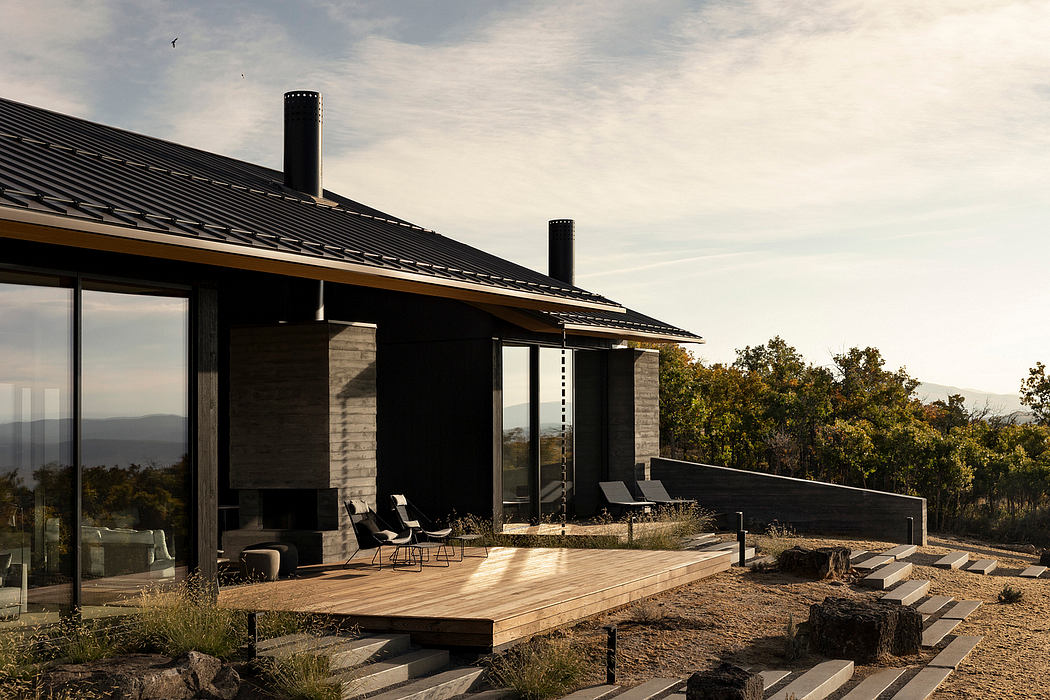 Modern cabin-style home with dark wood exterior, expansive deck, and scenic mountain views.