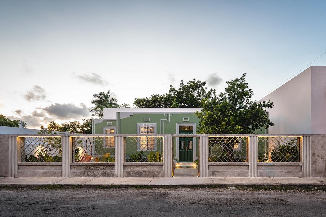 A vibrant green building with a decorative metal fence, surrounded by lush foliage.