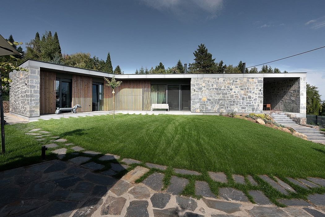 A modern single-story home with stone walls, wooden siding, and a lush green lawn.