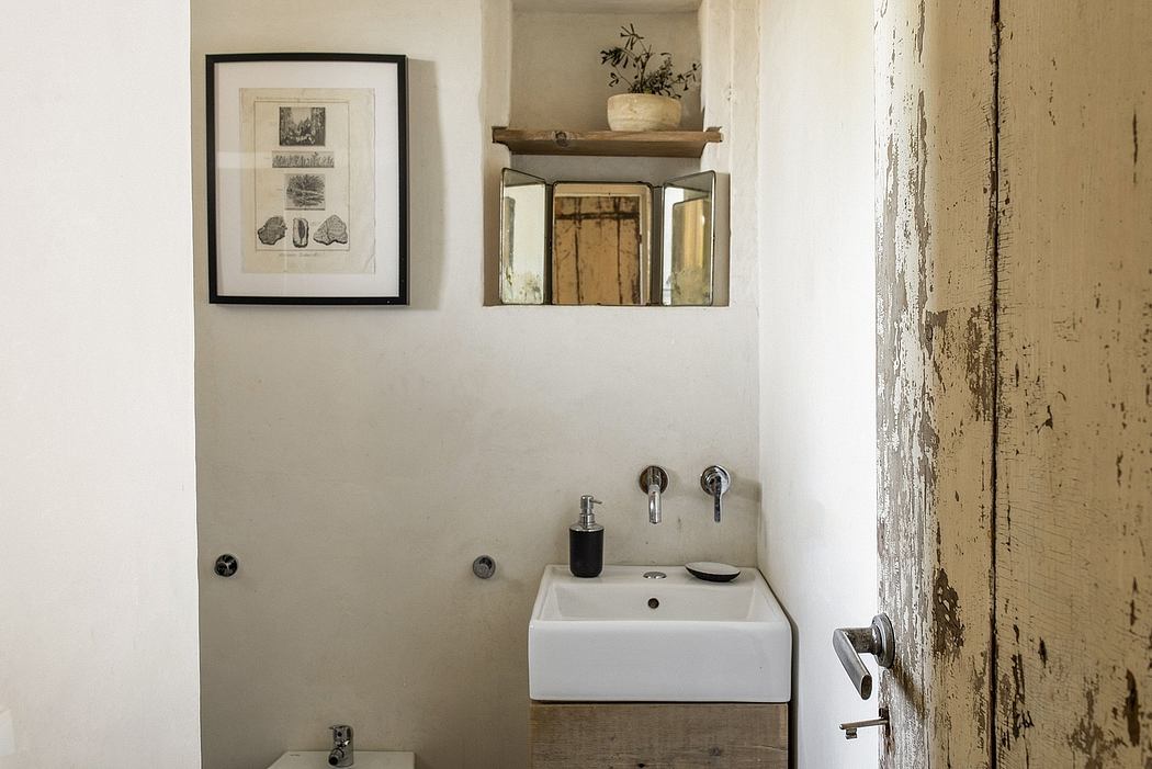 A rustic and minimalist bathroom with a vintage wooden shelf, vessel sink, and framed decor.