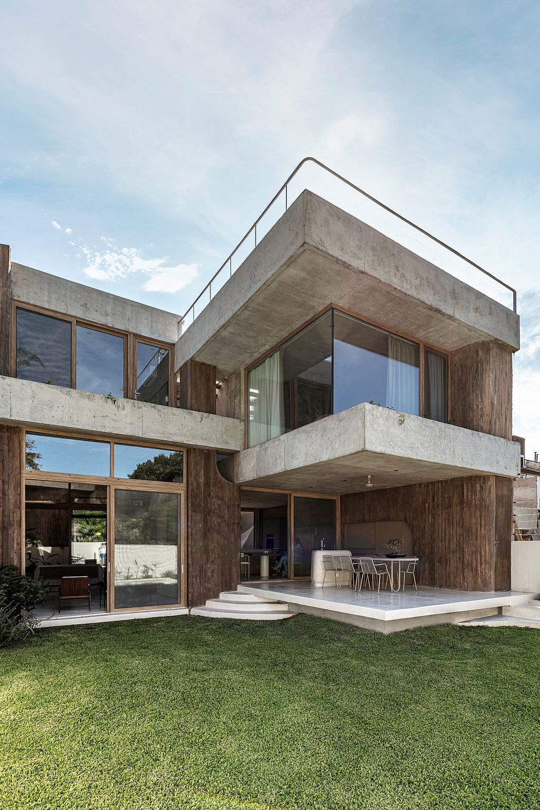 Striking concrete and wood architectural design with expansive glass walls and an outdoor patio.
