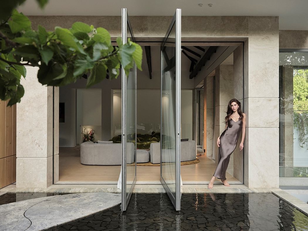 Sleek, modern architectural design with glass walls, stone terrace, and lush greenery.