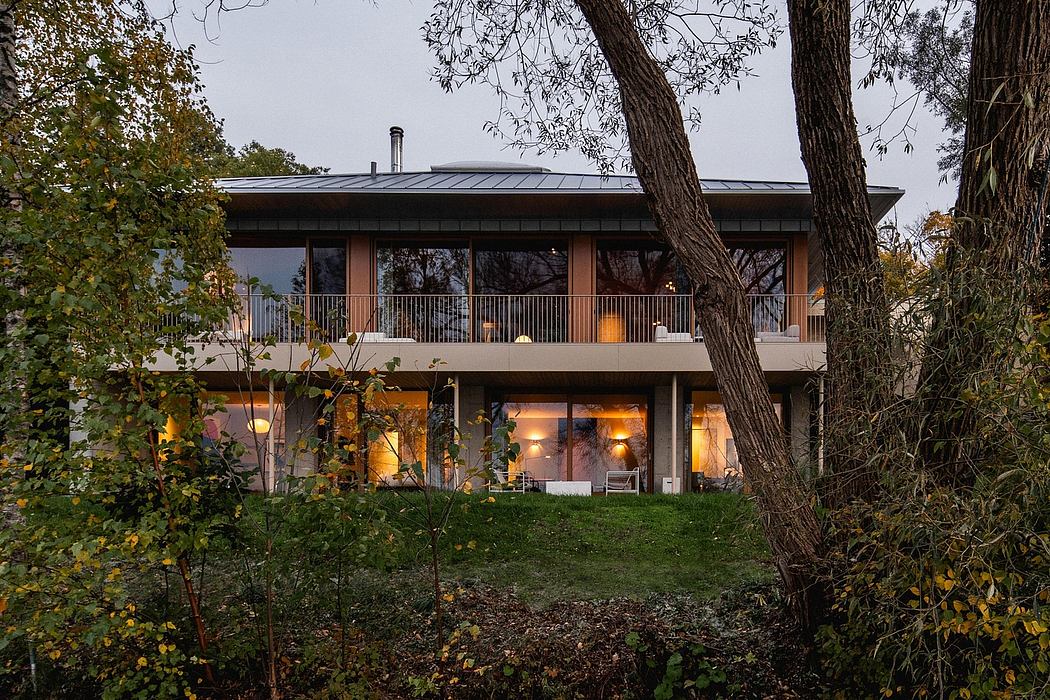 Contemporary home with large windows, covered balcony, and warm interior lighting.