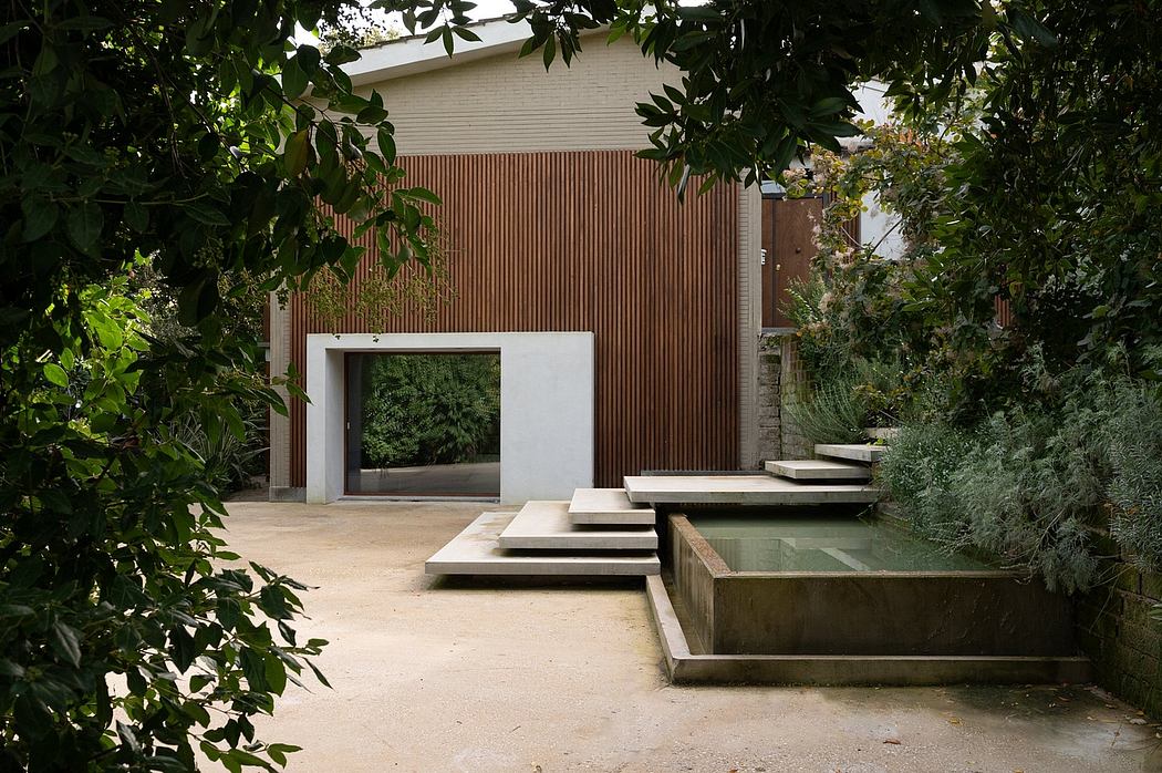A modernist outdoor space with wood-paneled walls, concrete steps, and a water feature.