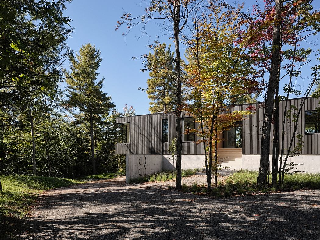 A modern, angular building amid vibrant fall foliage, with a gravel path leading to the entrance.