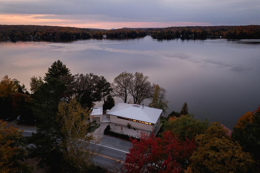 A lakeside building with a metal roof, surrounded by vibrant fall foliage.
