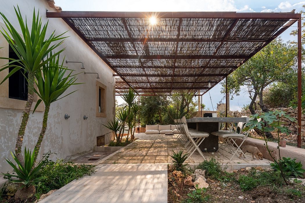 Rustic outdoor patio with thatched roof, stone walkway, and lush greenery.