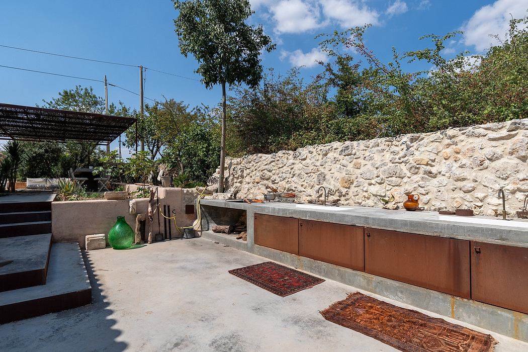 Outdoor kitchen area with stone wall, concrete countertops, and colorful pottery accents.