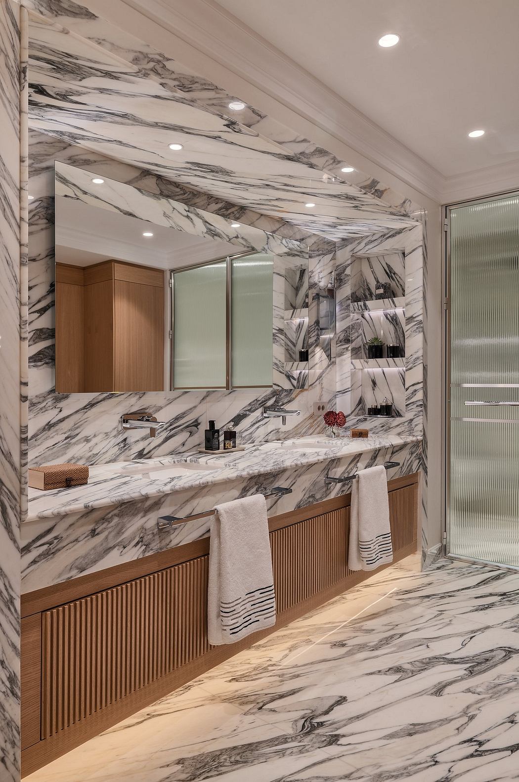 Striking marble bathroom with sleek wood vanity and recessed lighting design.