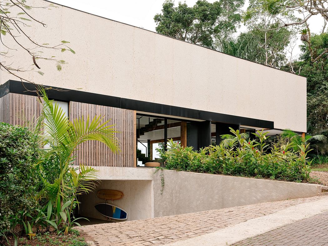Modern tropical villa with wooden siding, concrete walls, and lush foliage.