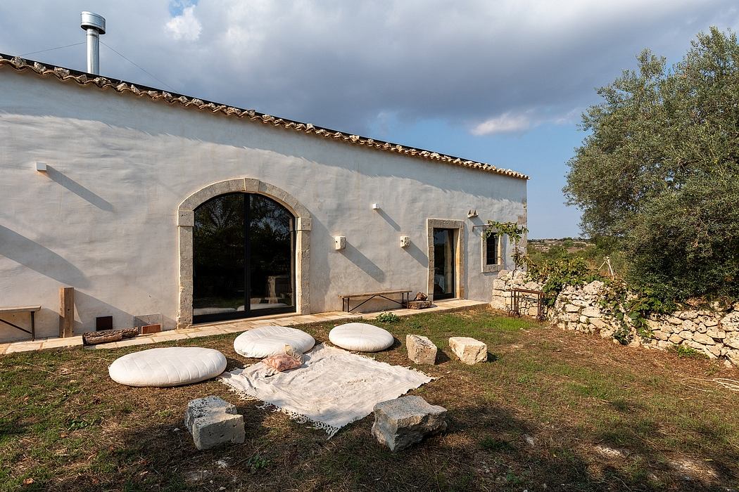 Old stone building with arched windows, seating area, and landscaped outdoor space.