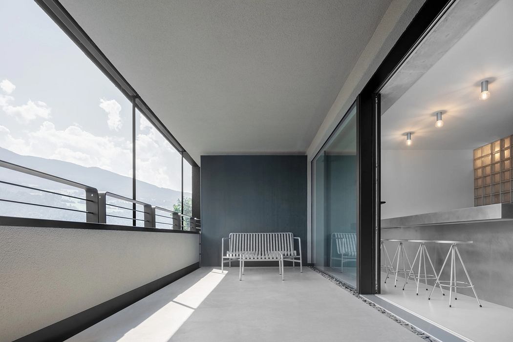 A modern balcony with minimalist furniture, sleek glass doors, and a clean, contemporary design.