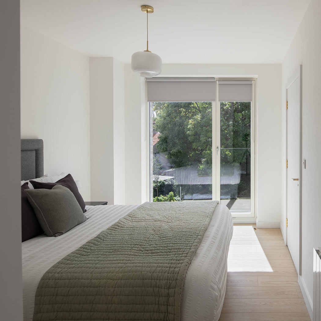 Spacious bedroom with large window overlooking lush greenery and modern pendant light.