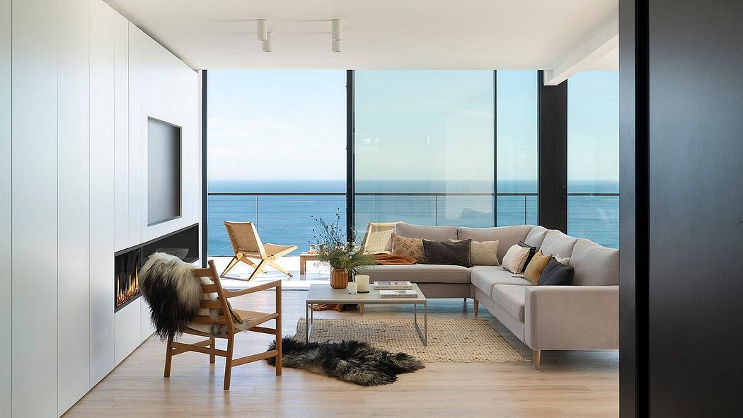 Spacious living area with large windows overlooking the ocean, featuring a cozy sectional sofa and wooden furniture.