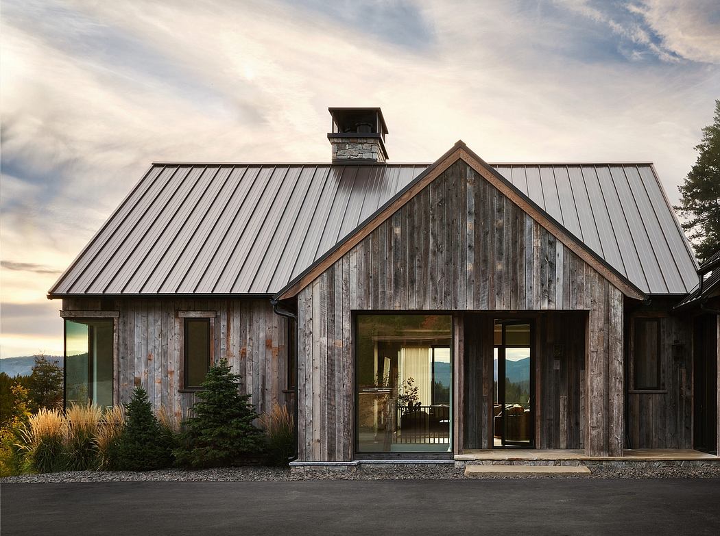 A rustic, modern cabin with a metal roof, wooden siding, and large windows offering a scenic view.
