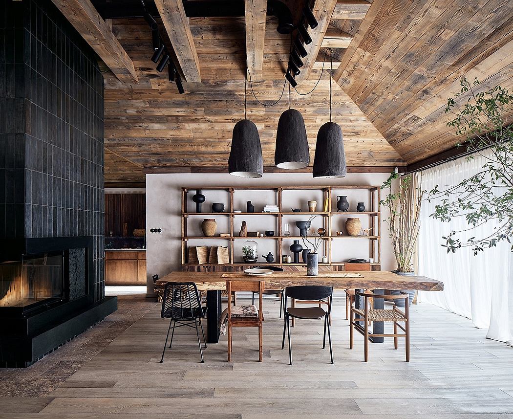 Rustic open-concept dining room with exposed wooden beams, stone fireplace, and curated shelving.