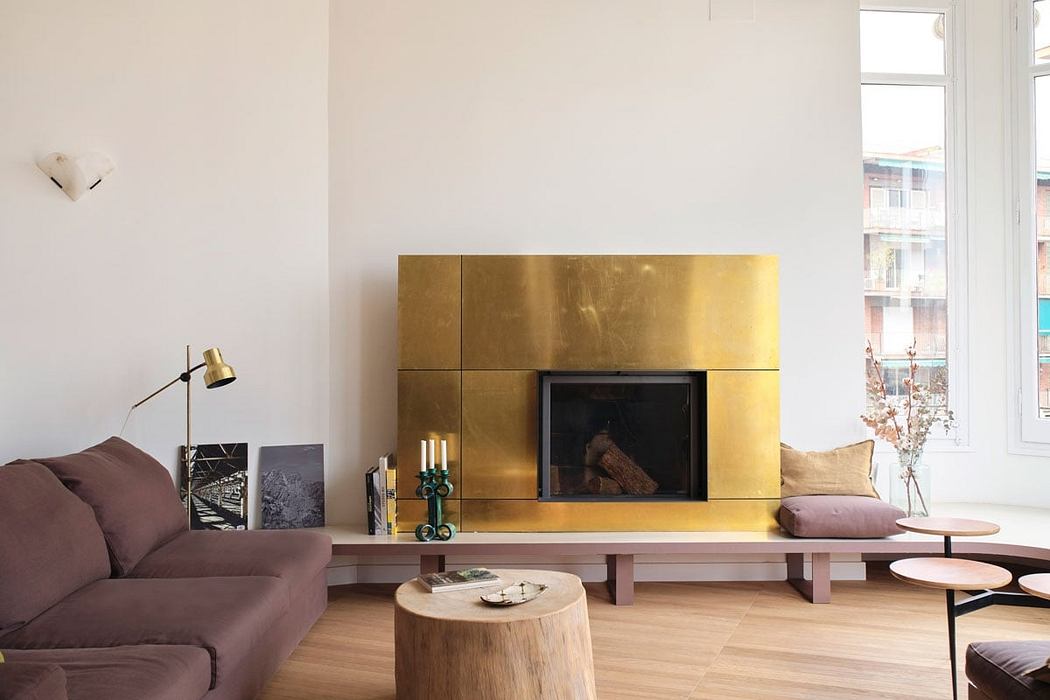 Modern living room with minimalist gold-tiled fireplace, wooden furniture, and natural lighting.