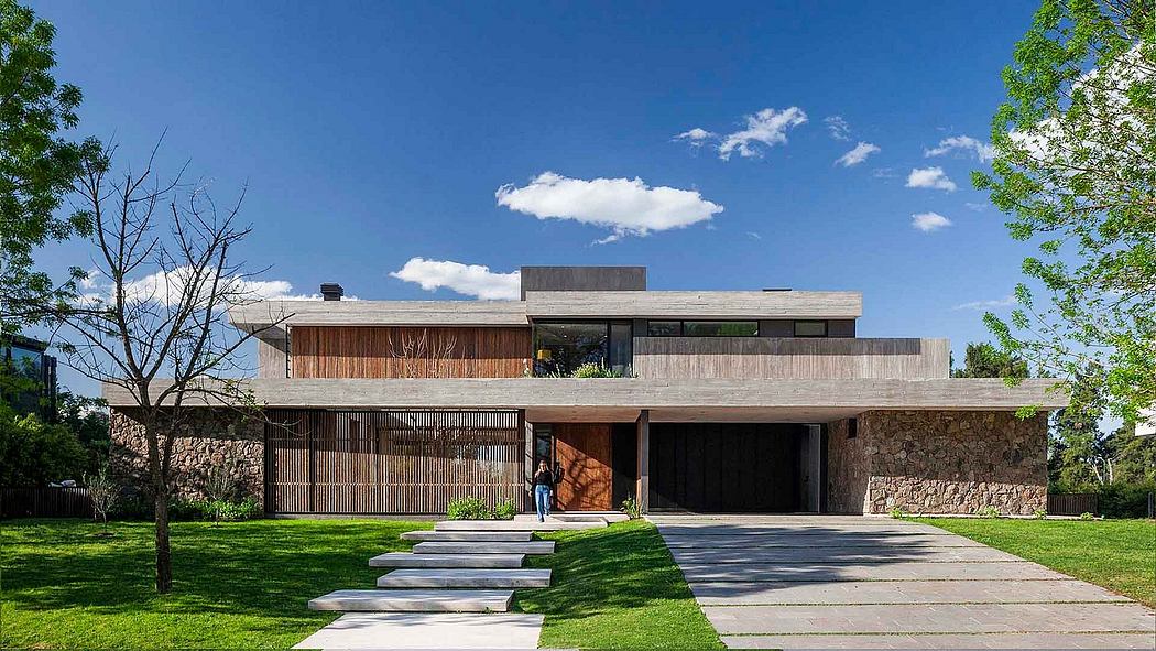 A modern, two-story home with a mix of wood, stone, and glass elements, surrounded by lush greenery.