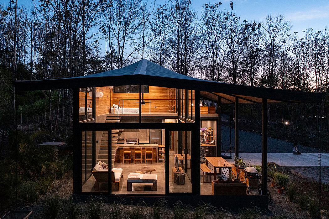 A modern, glass-enclosed cabin nestled in a wooded setting, featuring an open-concept interior.