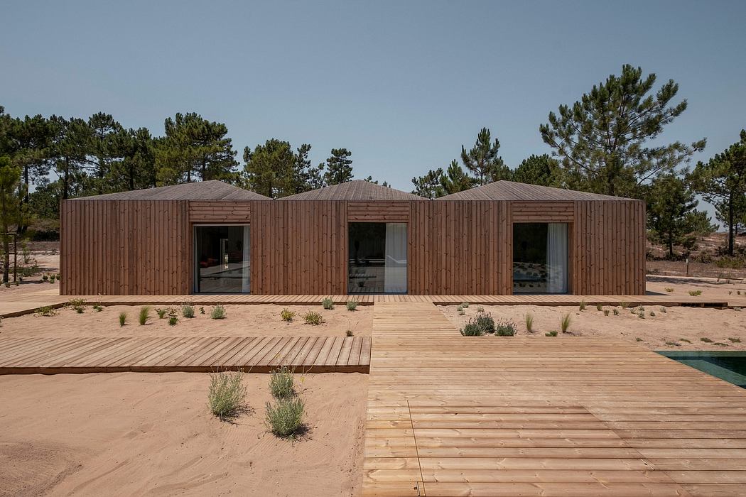 Contemporary wooden exterior with expansive windows and elevated wood deck overlooking natural landscape.