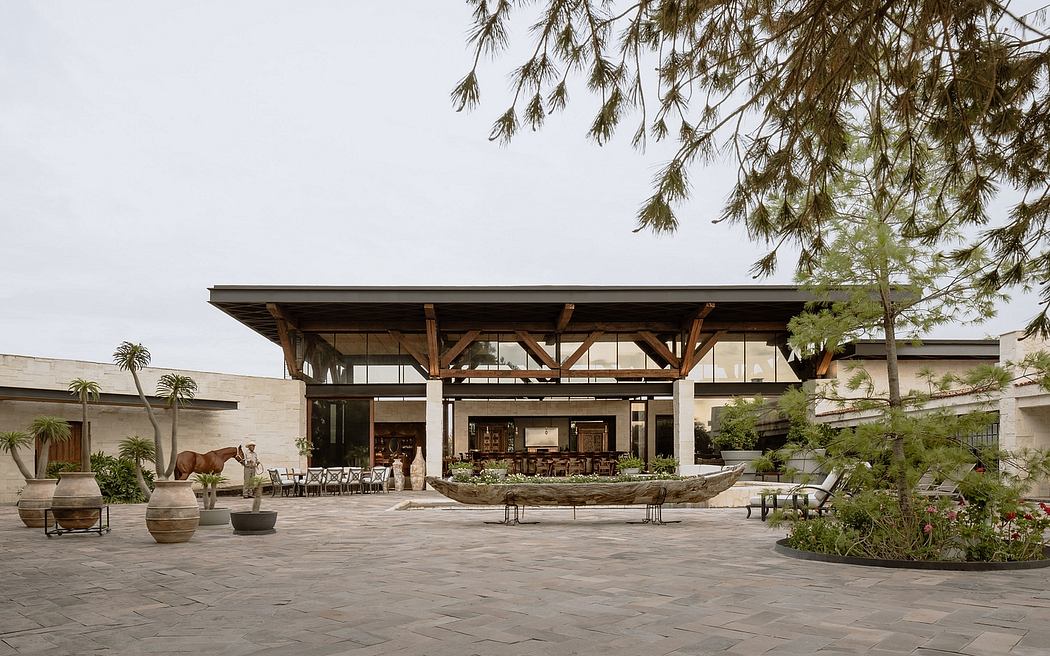 A spacious, open-air pavilion with wooden beams and a thatched roof, surrounded by lush greenery.